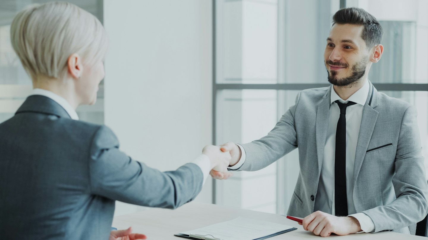 Two professionals shaking hands across a table