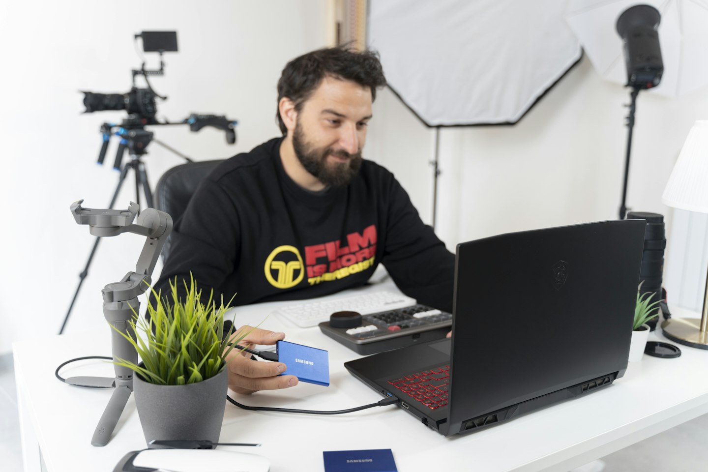 a man sitting at a desk with a laptop and a camera